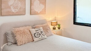 Ein Schlafzimmer mit einem Bett, einem Nachttisch, einer Lampe und Wandbildern.