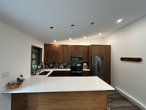 Eine moderne Küche mit einer zentralen Kochinsel, Edelstahlgeräten und Holzschränken.