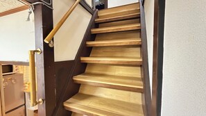 Eine Holztreppe mit dunkler Handlauf und heller Wand.