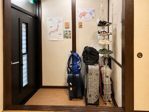 Ein Flur mit einer Tür, einer Karte Japans, einer Weltkarte und einem Schuhregal mit verschiedenen Schuhen.
