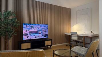 Una sala de estar moderna con televisor, una mesa de comedor, sillas y un panel decorativo en la pared.