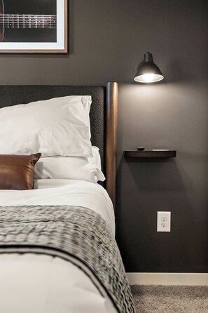 A neatly made bed with white and patterned bedding, a brown pillow, and a headboard. - Modern Condo-5 Min to Broadway -Walk to Coffee (Nashville)