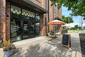 A storefront with a sign reading 'VANNIES TABLE' and 'GROCERY,' a sidewalk with a chalkboard sign saying 'Happy Hour,' and a potted plant on the ground. - Modern Condo-5 Min to Broadway -Walk to Coffee (Nashville)