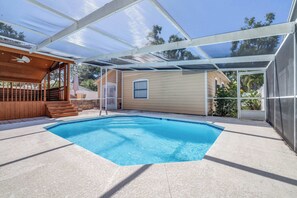 Ein überdachter Pool mit Holzterrasse und Treppen zu einer überdachten Terrasse.