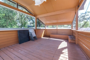 Eine überdachte Terrasse im Freien mit Holzwerteln, einer Bank und einem Klappstuhl.