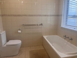 A bathroom with a toilet, a bathtub, and a shower area. - Waterfront escape with lake views, private pontoon & balcony, 5 mins to beach. (Tennyson)