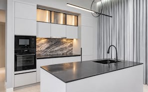 A modern kitchen with a built-in oven, microwave, and a marble backsplash. - 3 bedrooms Villa PRIMA with pool by TVC (Tambon Choeng Thale)
