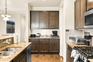 A modern kitchen with dark wooden cabinets, granite countertops, and stainless steel appliances. - Respite in the Pines | San Francisco Peaks Views | 3BR (Flagstaff)