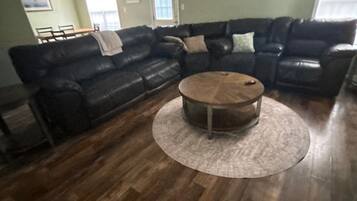 Ein Wohnzimmer mit einem Ecksofa, einem runden Couchtisch und Holzböden.