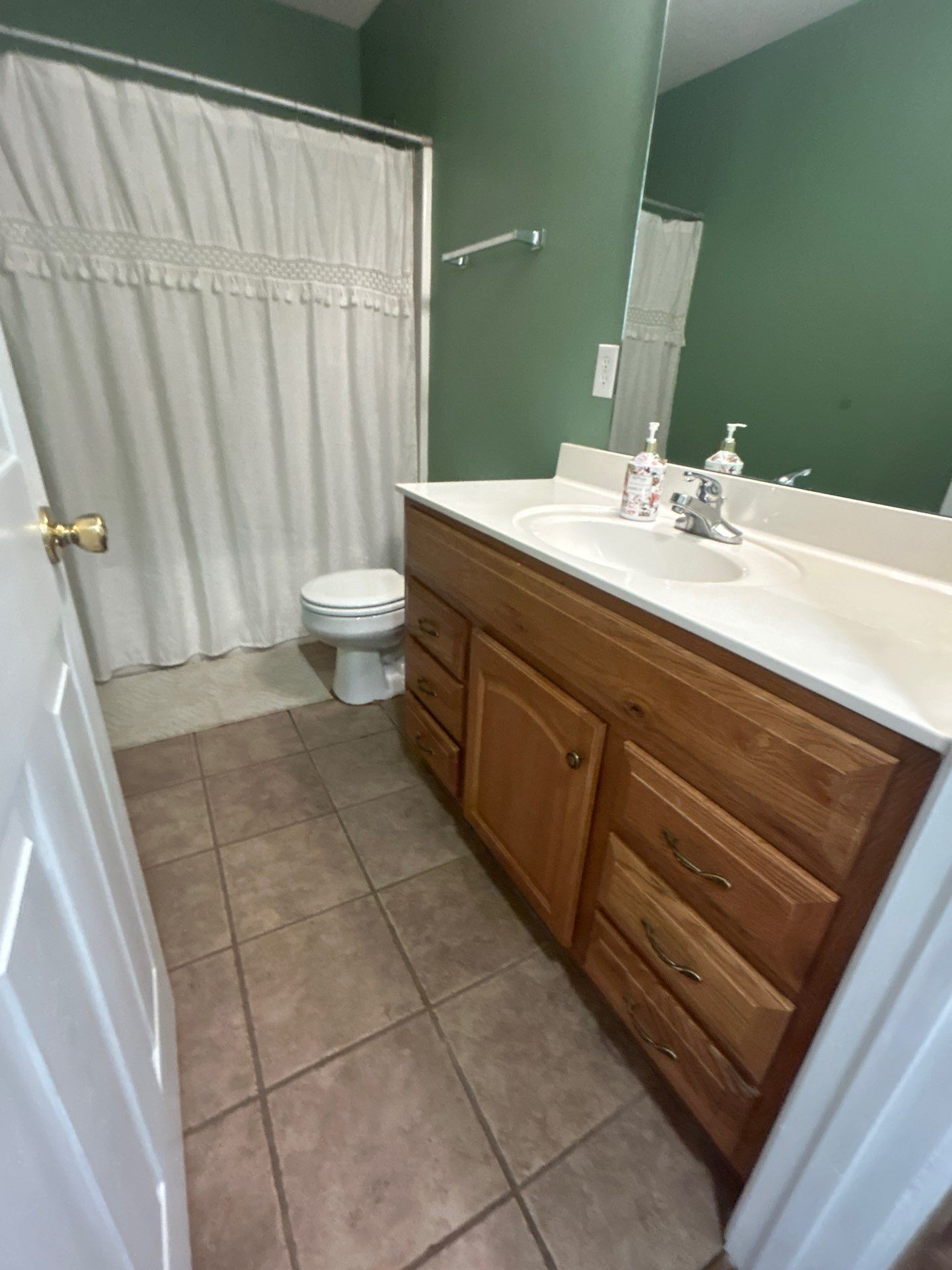 A bathroom with a toilet, a sink with a mirror, and a shower curtain.