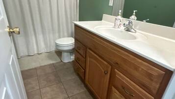 A bathroom with a toilet, a sink with a mirror, and a shower curtain.