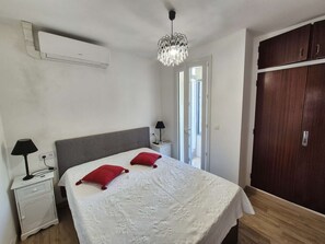 Ein Schlafzimmer mit einem Bett, einem Nachttisch, einer Lampe, einem Kleiderschrank und einer Deckenleuchte.