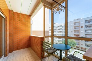 Ein Balkon mit einer Ziegelwand, einem Tisch und zwei Stühlen.