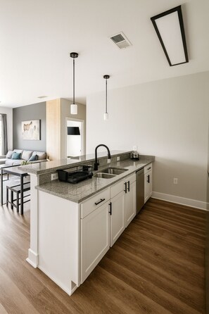A modern kitchen with white cabinetry, a granite countertop, and a black faucet. - Spacious 2BR/2BA Condo Across from UAB 3F (Birmingham)