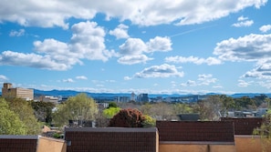 A cityscape with a clear sky, buildings, and distant mountains. - Garran Treetop Views - Balcony & Mountain Sunsets (Garran)