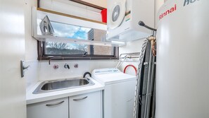 A compact kitchen with a sink, a window, and a drying rack. - Garran Treetop Views - Balcony & Mountain Sunsets (Garran)