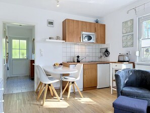 Eine moderne Küche mit Holzausstattung, einem eingebauten Ofen und einem Essbereich mit zwei Stühlen und einem Tisch.