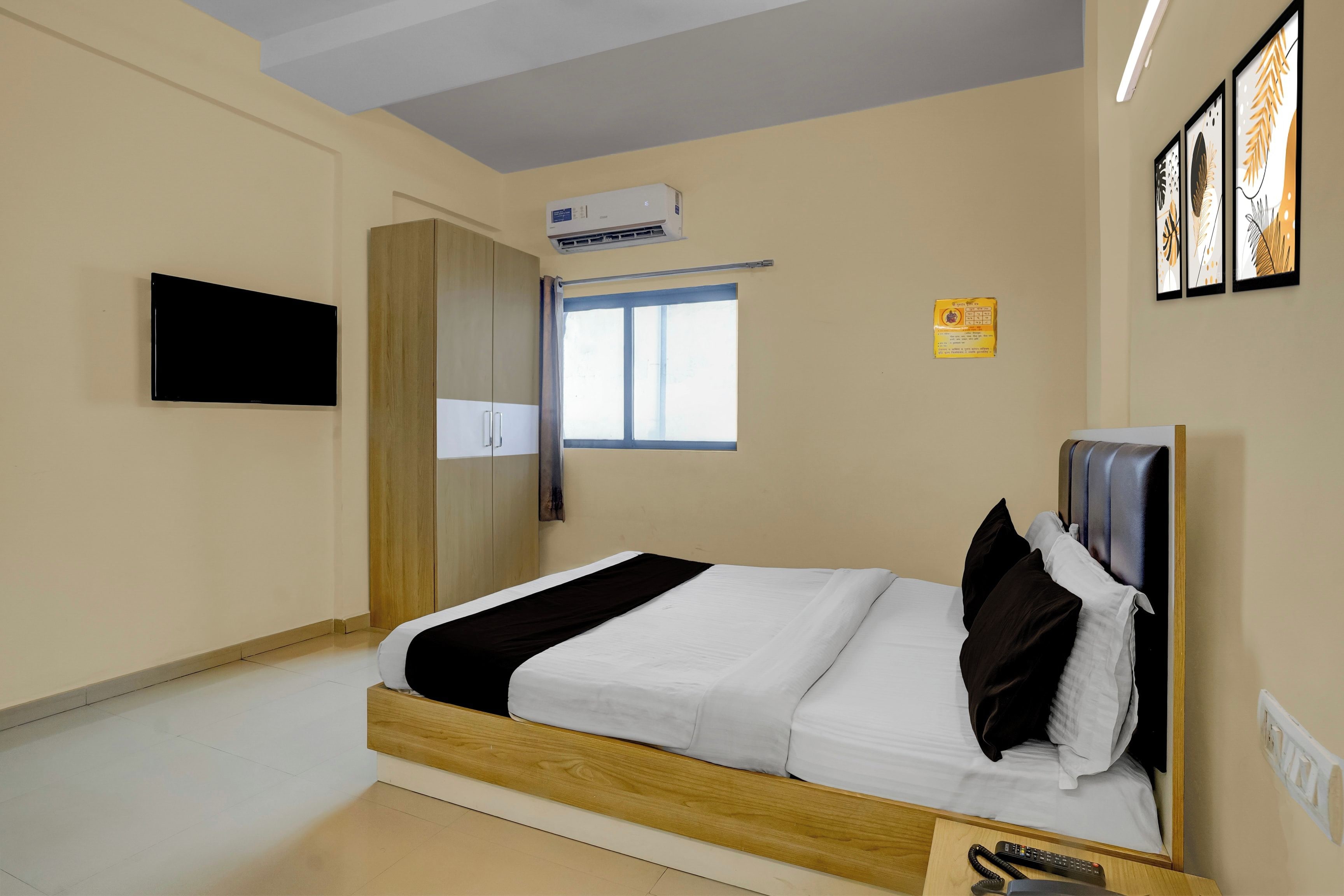 Habitación de hotel con cama, armario, aire acondicionado, ventana y televisor montado en la pared.