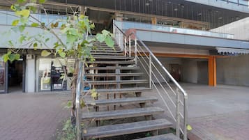 Una escalera conduce a un nivel superior de un edificio, con barandilla de metal.