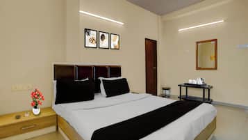 Habitación de hotel con cama, mesita de noche, obra de arte en la pared, un espejo y una mesita con bandeja.