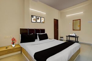Habitación de hotel con cama, mesita de noche, obra de arte en la pared, un espejo y una mesita con bandeja.