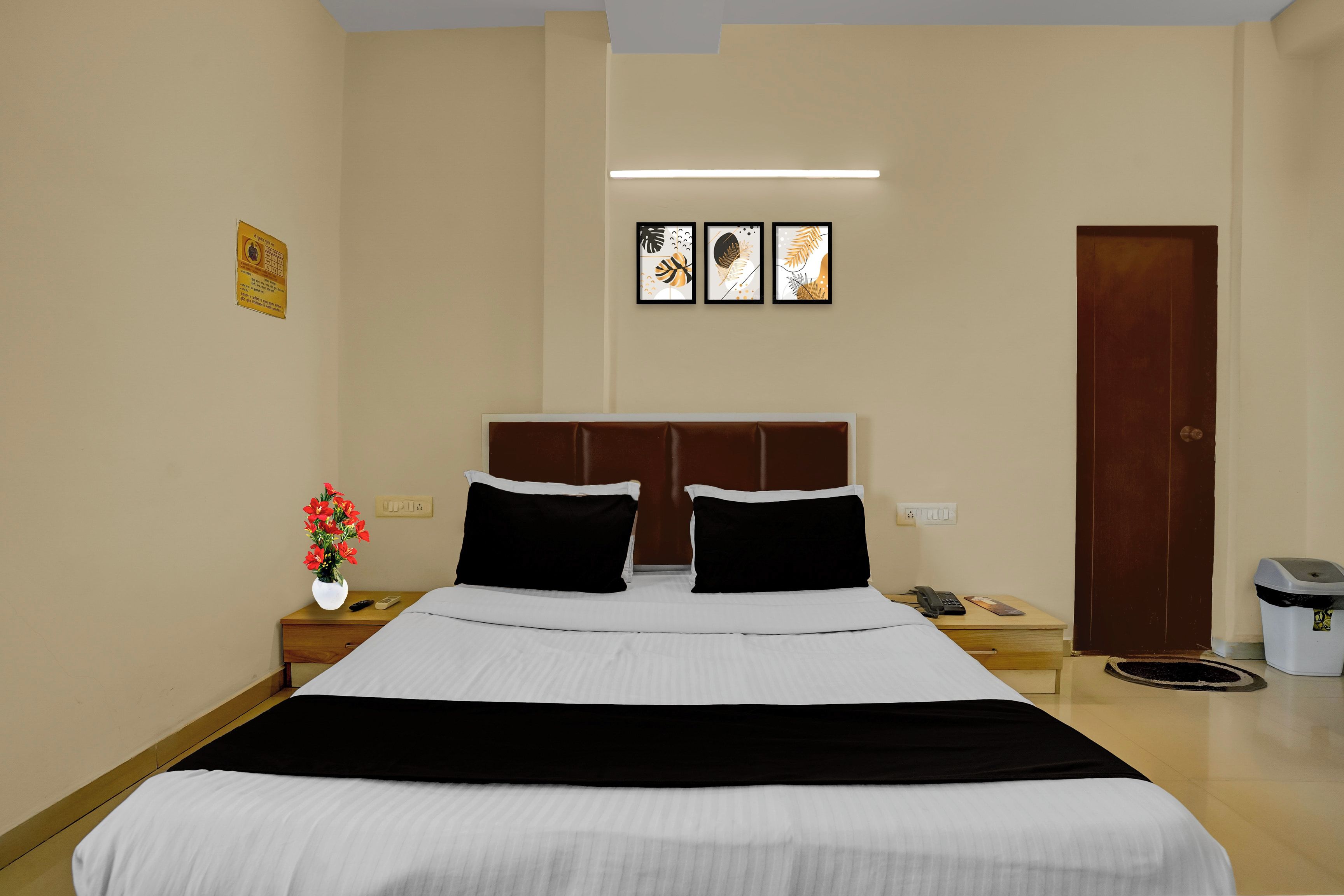 Una habitación de hotel con cama, mesitas de noche, lámpara de pared y puerta.
