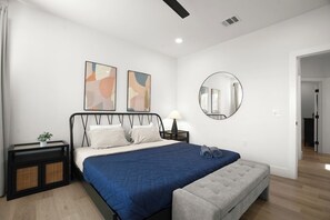 A bedroom with a bed, bedside tables, a lamp, a round mirror, and abstract wall art. - Private 3BR 2.5BA Home | Sleeps 9 | Fire Pit, BBQ + Fenced Yard | 15 Min to ATX (Austin)