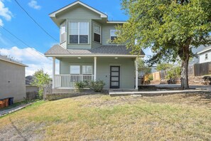 A two-story house with a front porch, a visible mailbox, and a tree in the yard. - Private 3BR 2.5BA Home | Sleeps 9 | Fire Pit, BBQ + Fenced Yard | 15 Min to ATX (Austin)