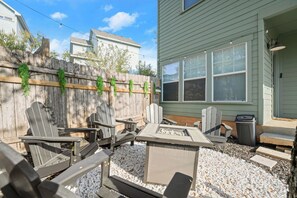An outdoor patio with Adirondack chairs, a fire pit, and a wooden fence. - Private 3BR 2.5BA Home | Sleeps 9 | Fire Pit, BBQ + Fenced Yard | 15 Min to ATX (Austin)
