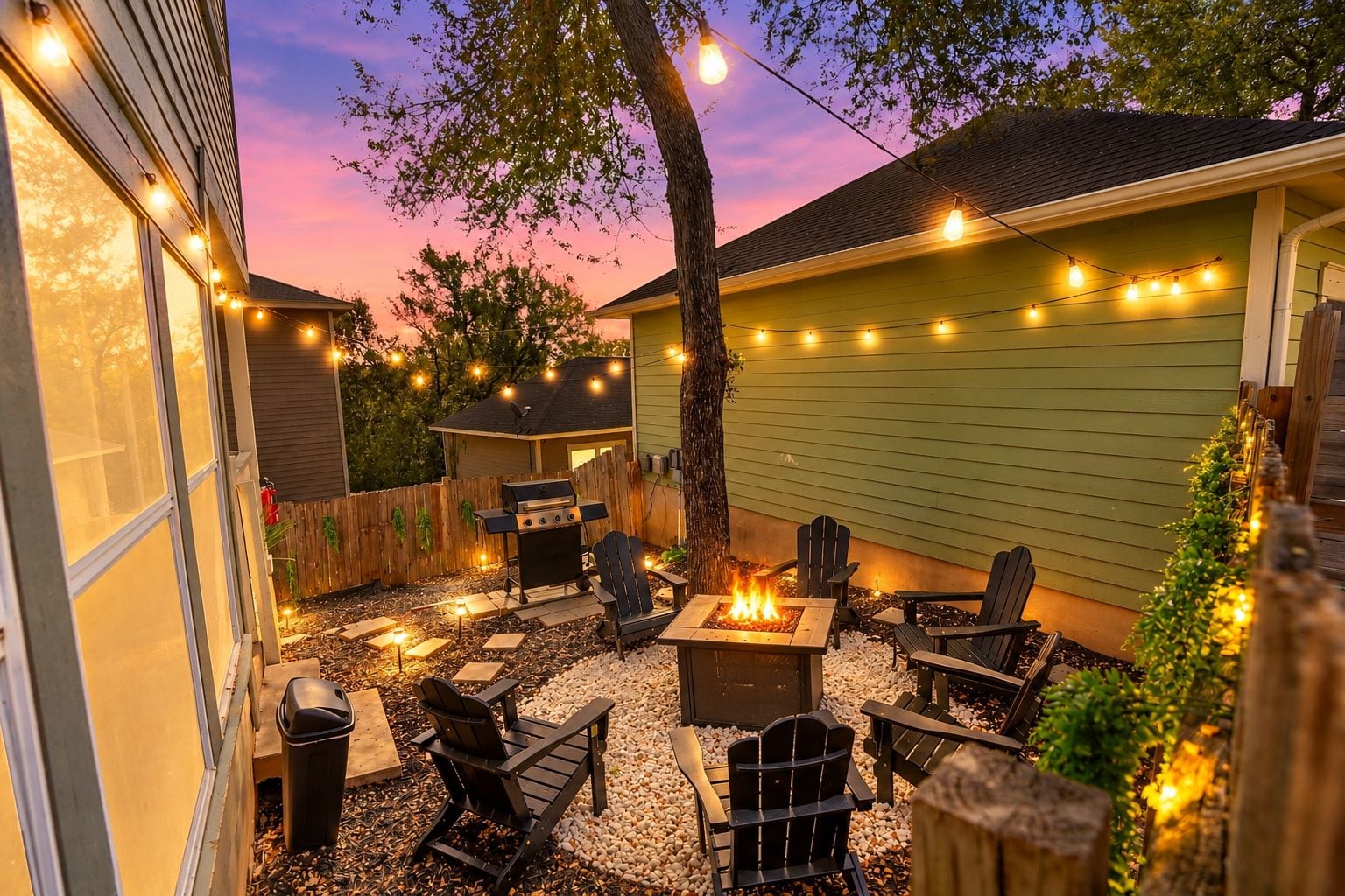 An outdoor patio with a fire pit, seating, and string lights.