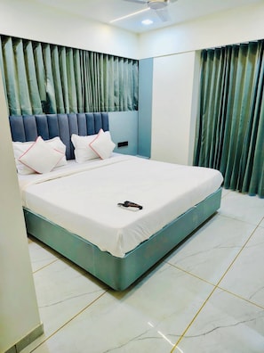 A modern bedroom with a large bed, a headboard with vertical slats, and a ceiling fan.