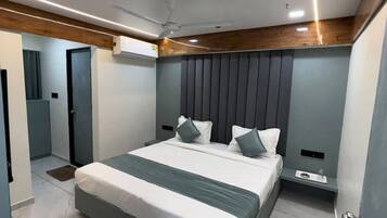 A modern bedroom with a large bed, a ceiling fan, and a small bedside table.