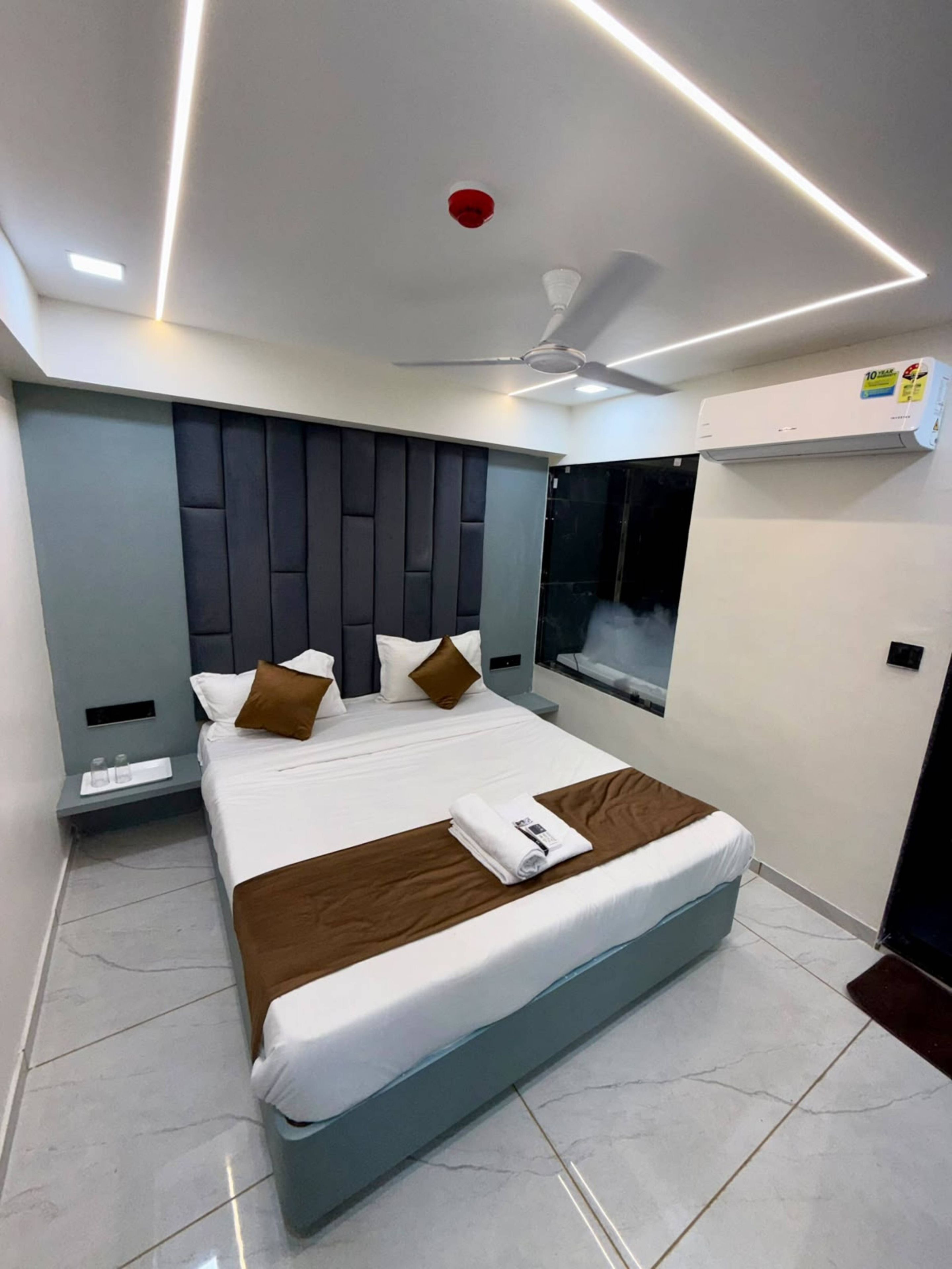 A modern hotel room with a large bed, a ceiling fan, and an air conditioning unit.