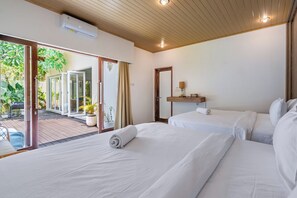 Habitación de hotel con dos camas, puerta corrediza de vidrio a un patio y ventilador de techo.