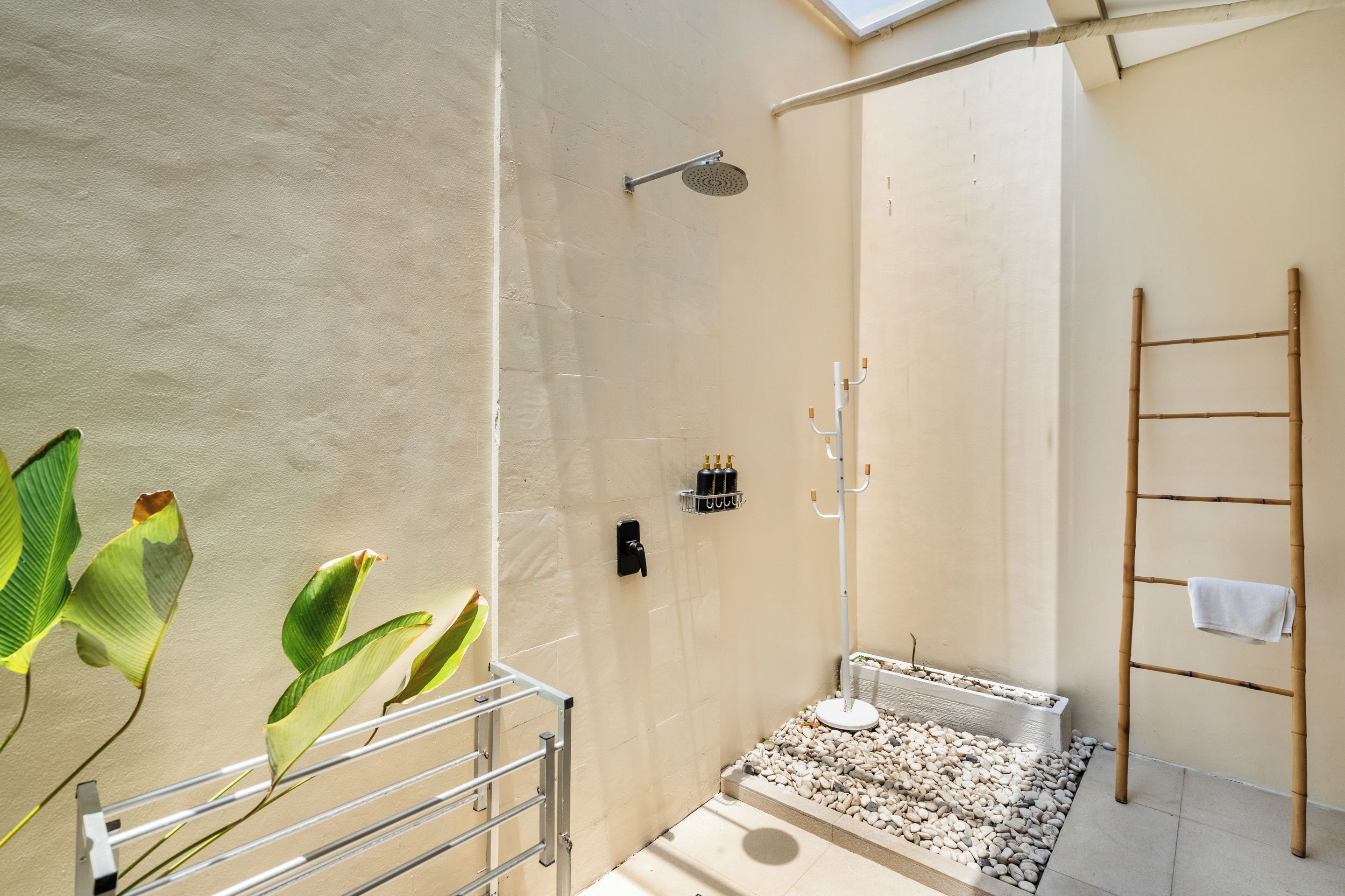 Une salle de bain moderne avec une douche, un porte-serviettes et un petit espace extérieur aménagé avec des galets.