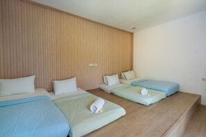 Habitación de hotel con tres camas, paneles de madera en las paredes y un diseño sencillo y limpio.