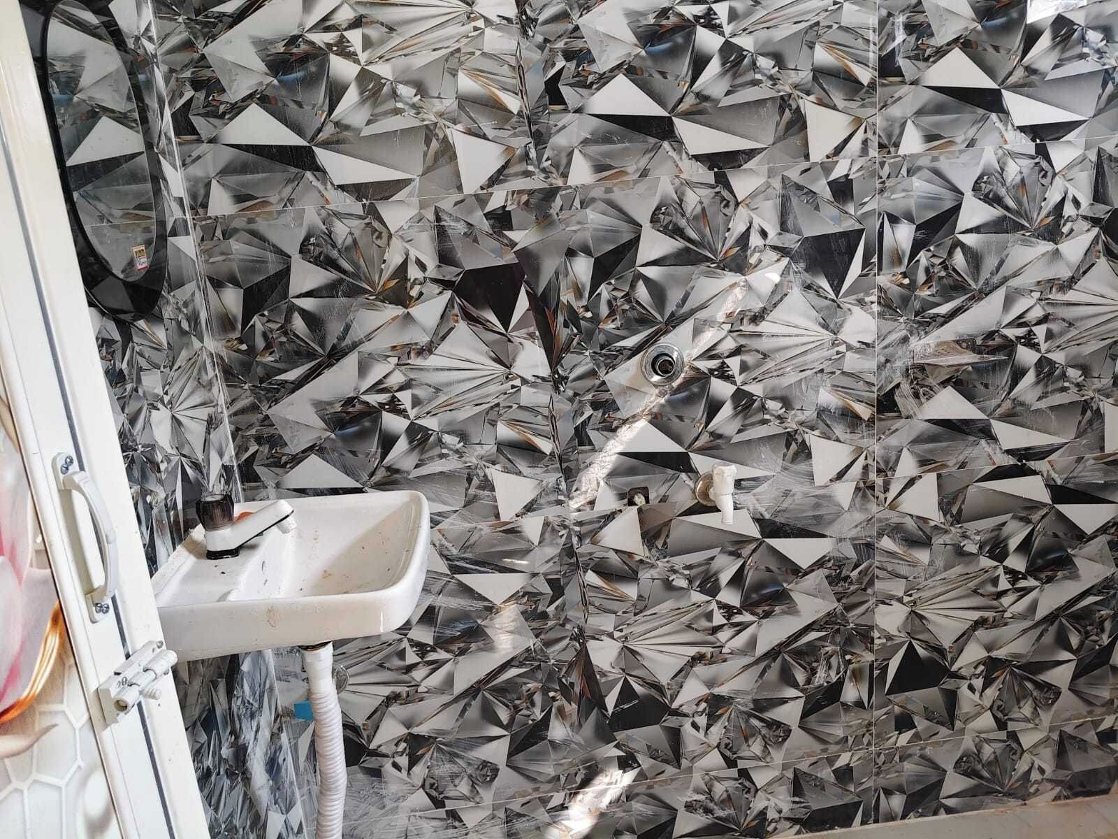 Een badkamer met een wastafel en een muur betegeld met reflecterende, geometrische tegels.