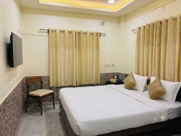 A hotel room with a bed, curtains, a chair, a television, and a small table with a cup. - Collection O Airport Crossway Formerly (Barasat)
