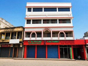A multi-story building with signage for Raj Polyclinic and Raj Pharmacy on the ground floor. - Collection O Airport Crossway Formerly (Barasat)