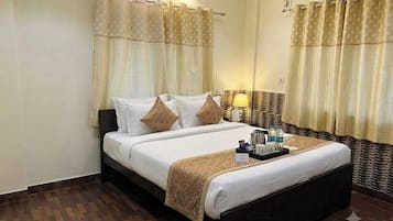 Habitación de hotel con cama, cortinas, mesita de noche con lámpara y bandeja con artículos de aseo.
