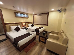 A hotel room with two beds, a sofa, a small table, and a TV mounted on the wall. - Collection O Airport Crossway Formerly (Barasat)