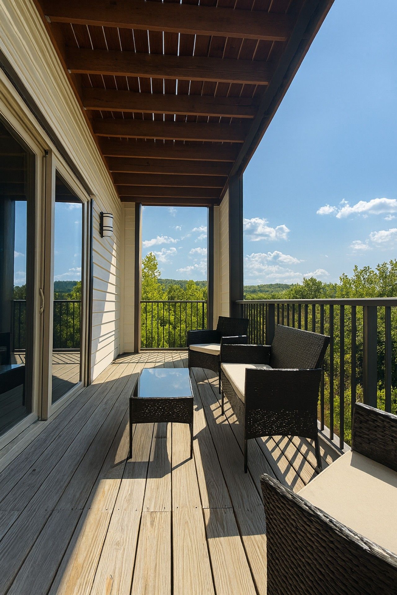 A covered deck with outdoor furniture and a view of the landscape.
