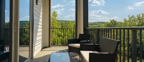 A covered deck with outdoor furniture and a view of the landscape.