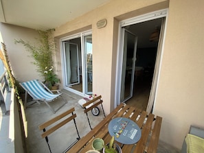 A balcony with a wooden bench, a striped lounge chair, and a table with a placemat. - Beautiful, cozy 3-room apartment with parking and a terrace (Bordeaux)