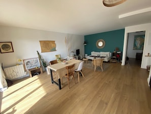A spacious living area with a dining table, chairs, a sofa, and a television. - Beautiful, cozy 3-room apartment with parking and a terrace (Bordeaux)