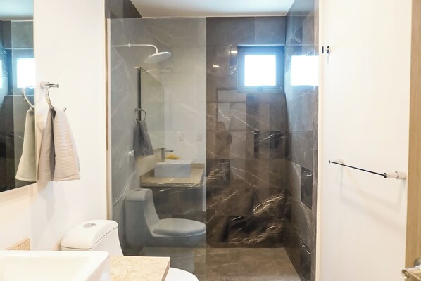 Un baño moderno con ducha de vidrio, inodoro y lavamanos.
