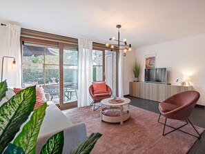 A modern living room with a sofa, two chairs, a coffee table, and a TV. - Modern holiday home with terrace by the coast (De Panne)