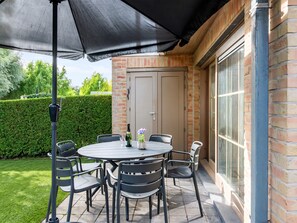 An outdoor patio with a round table and chairs, a black umbrella, and a bottle of wine. - Modern holiday home with terrace by the coast (De Panne)