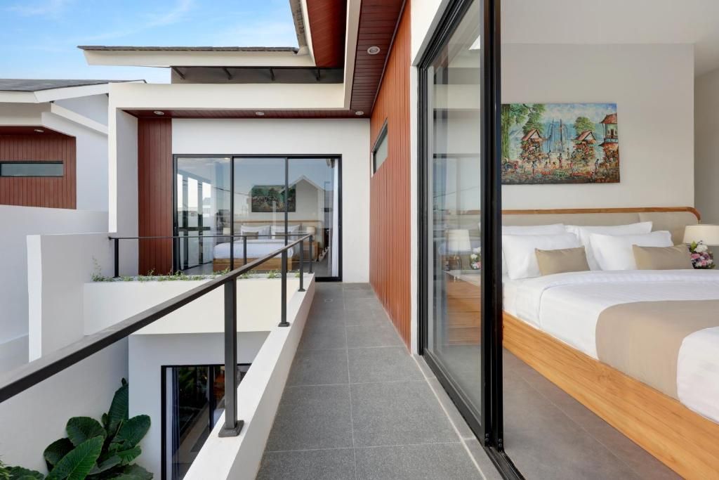 Una habitación de hotel moderna con balcón, cama con ropa blanca y un cuadro en la pared.