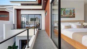 Una habitación de hotel moderna con balcón, cama con ropa blanca y un cuadro en la pared.